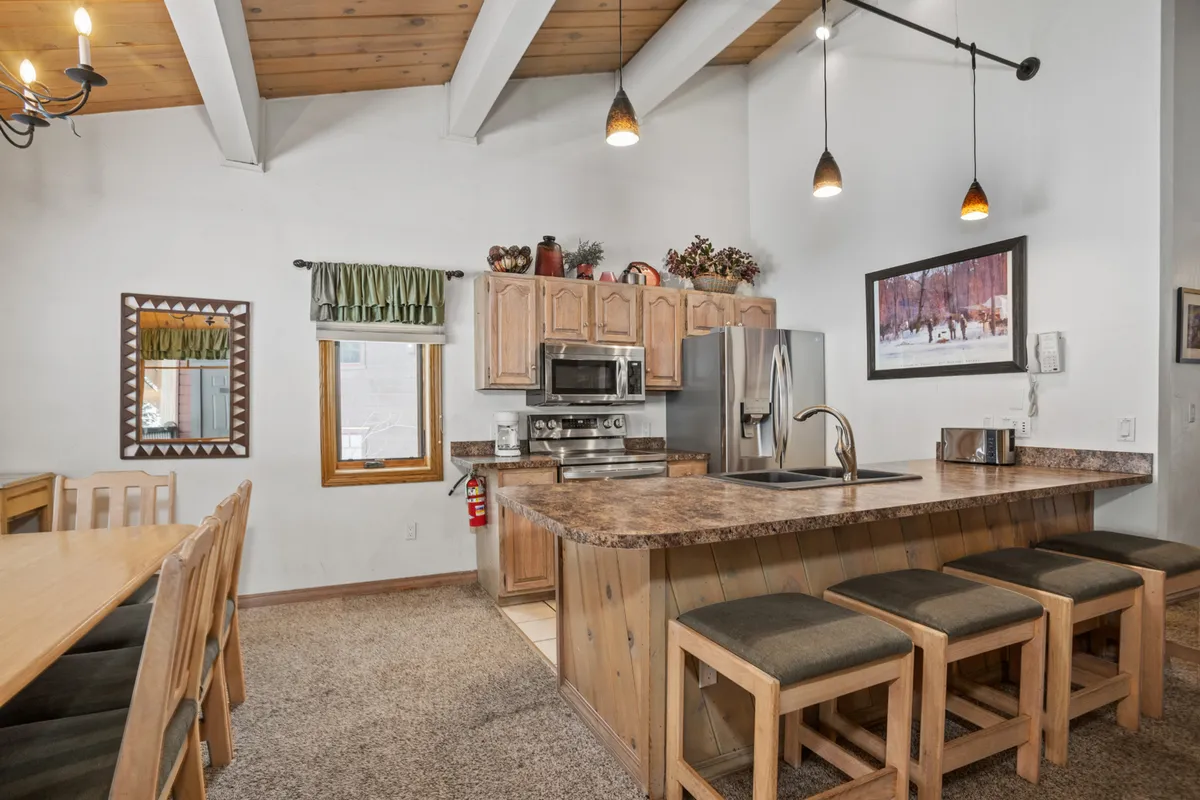 A spacious, open-concept interior with a central kitchen island, large dining table, and stylish decor, reflecting modern upgrades. The scene highlights the kitchen—a key feature for eco-conscious travelers seeking modern appliances and convenience during their stay.