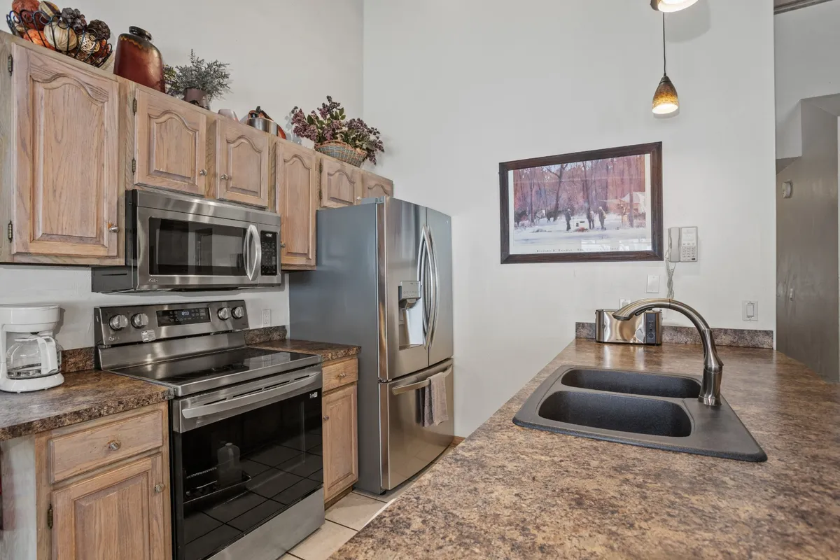 A close-up view of a sleek kitchen featuring stainless steel appliances, a central island sink, and tasteful decorative accents, demonstrating both style and practicality. This image underscores the property’s commitment to modern, efficient living—appealing to those who value sustainability.